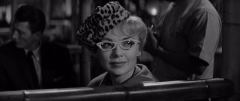 Movie still from “The Apartment” (1960), directed by Billy Wilder – A black and white photo of a woman wearing glasses and a hat; Close Up shot, Low angle