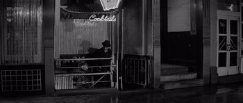 Movie still from “The Apartment” (1960), directed by Billy Wilder – A man sitting in front of a bar at night; Wide shot, High angle