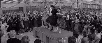 Movie still from “The Apartment” (1960), directed by Billy Wilder – A black and white photo of a group of people on a stage; Wide shot, Low angle