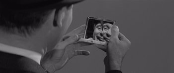 Movie still from “The Apartment” (1960), directed by Billy Wilder – A man holding a mirror with a picture of a man's face in it; Extreme Close Up shot, Over the shoulder angle