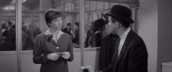 Movie still from “The Apartment” (1960), directed by Billy Wilder – A man and a woman talking in front of a camera; Medium shot, Over the shoulder angle