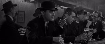 Movie still from “The Apartment” (1960), directed by Billy Wilder – Two men sitting at a table smoking and drinking; Medium shot, Low angle