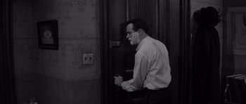 Movie still from “The Apartment” (1960), directed by Billy Wilder – A black and white photo of a man talking on a phone; Medium shot, High angle