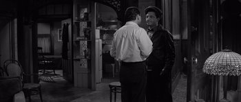 Movie still from “The Apartment” (1960), directed by Billy Wilder – Two men standing next to each other in front of a doorway; Medium shot, Over the shoulder angle