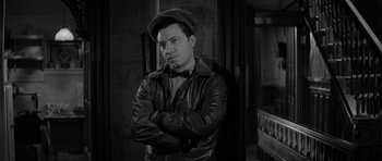 Movie still from “The Apartment” (1960), directed by Billy Wilder – A black and white photo of a man with his arms crossed; Medium shot, Over the shoulder angle