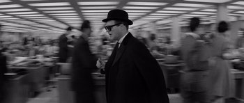 Movie still from “The Apartment” (1960), directed by Billy Wilder – A black and white photo of a man in a suit and hat; Medium shot, Over the shoulder angle
