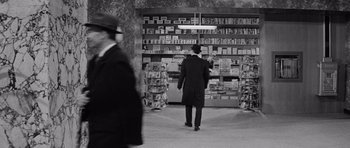 Movie still from “The Apartment” (1960), directed by Billy Wilder – A man walking in front of a book store; Wide shot, Over the shoulder angle