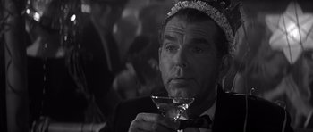 Movie still from “The Apartment” (1960), directed by Billy Wilder – A black and white photo of a man holding a martini glass; Close Up shot, High angle