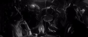 Movie still from “The Apartment” (1960), directed by Billy Wilder – A black and white photo of a group of people gathered around a table; Medium shot, High angle