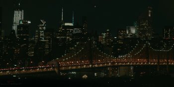 Movie still from “The Assistant” (2019), directed by Kitty Green – A view of a bridge and a city skyline at night time; Extreme Wide shot, High angle