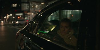Movie still from “The Assistant” (2019), directed by Kitty Green – A woman sitting in the back seat of a black car; Close Up shot, Over the shoulder angle