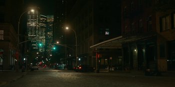 Movie still from “The Assistant” (2019), directed by Kitty Green – A city street at night lit by street lights; Extreme Wide shot, High angle