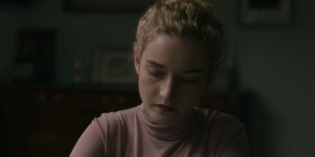 Movie still from “The Assistant” (2019), directed by Kitty Green – A woman with blonde hair sitting in front of a window; Close Up shot, Over the shoulder angle