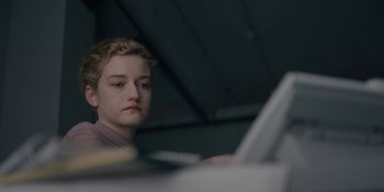 Movie still from “The Assistant” (2019), directed by Kitty Green – A woman sitting in front of a computer monitor; Close Up shot, Low angle