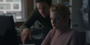 Movie still from “The Assistant” (2019), directed by Kitty Green – A man and a woman sitting next to each other in front of a computer screen; Medium shot, Over the shoulder angle