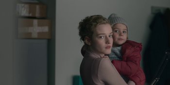 Movie still from “The Assistant” (2019), directed by Kitty Green – A woman and a child are looking at the camera; Close Up shot, Over the shoulder angle