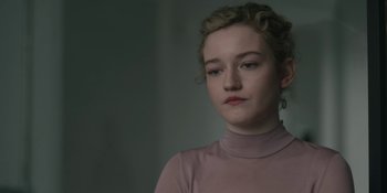 Movie still from “The Assistant” (2019), directed by Kitty Green – A young woman in a pink shirt is looking at the camera; Close Up shot, Over the shoulder angle