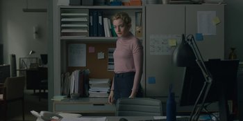Movie still from “The Assistant” (2019), directed by Kitty Green – A woman standing in front of a desk in an office; Medium shot, Over the shoulder angle