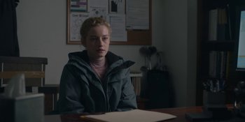 Movie still from “The Assistant” (2019), directed by Kitty Green – A woman sitting at a table in a room; Medium shot, Over the shoulder angle