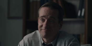 Movie still from “The Assistant” (2019), directed by Kitty Green – A person sitting in front of a window; Close Up shot, Over the shoulder angle