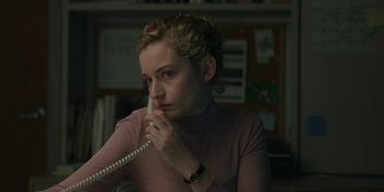 Movie still from “The Assistant” (2019), directed by Kitty Green – A woman holding a phone to her ear while sitting in a chair; Close Up shot, Over the shoulder angle