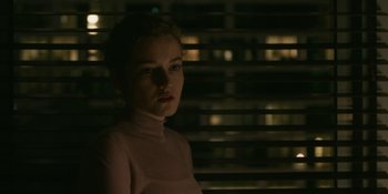 Movie still from “The Assistant” (2019), directed by Kitty Green – A woman in a pink shirt is standing in front of a window; Close Up shot, Over the shoulder angle