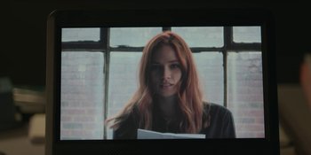 Movie still from “The Assistant” (2019), directed by Kitty Green – A woman with long red hair is holding papers; Close Up shot, Low angle