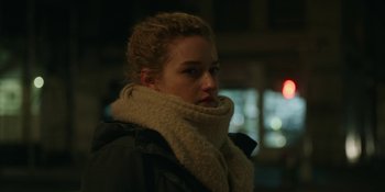 Movie still from “The Assistant” (2019), directed by Kitty Green – A young woman wearing a coat and a scarf; Close Up shot, Over the shoulder angle
