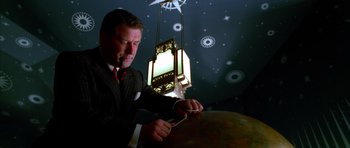 Movie still from “The Aviator” (2004), directed by Martin Scorsese – A man in a suit and tie cutting a globe; Medium shot, Low angle