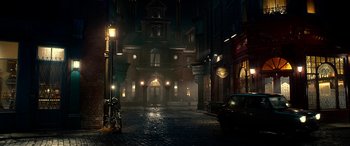 Movie still from “The BFG” (2016), directed by Steven Spielberg – A dark city street with a building lit up at night; Extreme Wide shot, High angle