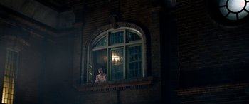Movie still from “The BFG” (2016), directed by Steven Spielberg – A woman standing in a window sill looking out of a window; Wide shot, Low angle