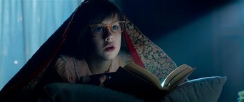 Movie still from “The BFG” (2016), directed by Steven Spielberg – A girl with glasses is reading a book in the dark; Close Up shot, Low angle