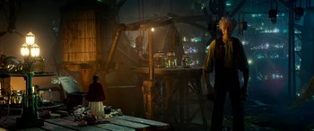 Movie still from “The BFG” (2016), directed by Steven Spielberg – A man standing in front of a table with jars on top of it; Wide shot, Over the shoulder angle