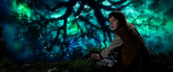 Movie still from “The BFG” (2016), directed by Steven Spielberg – A young girl sitting in front of a projection of a tree; Medium shot, Low angle