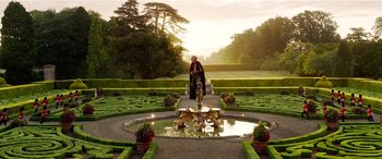 Movie still from “The BFG” (2016), directed by Steven Spielberg – A person standing in front of a fountain in a garden; Extreme Wide shot, High angle