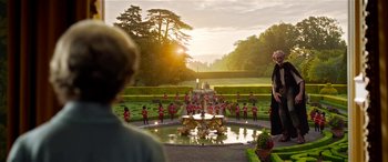 Movie still from “The BFG” (2016), directed by Steven Spielberg – A group of people standing around a fountain in a garden; Extreme Wide shot, Over the shoulder angle
