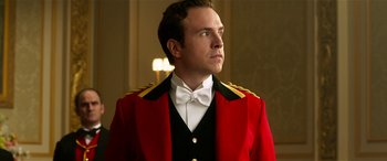 Movie still from “The BFG” (2016), directed by Steven Spielberg – A man in a red jacket and a white bow tie; Close Up shot, Low angle