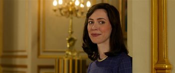 Movie still from “The BFG” (2016), directed by Steven Spielberg – A woman in a blue checkered dress is smiling for the camera; Close Up shot, Over the shoulder angle