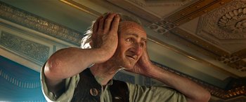Movie still from “The BFG” (2016), directed by Steven Spielberg – An old man with a beard is holding his hands up to his ears; Close Up shot, Low angle