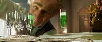 Movie still from “The BFG” (2016), directed by Steven Spielberg – A man sitting at a table with two glasses filled with green liquid; Close Up shot, Over the shoulder angle