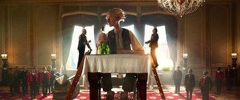 Movie still from “The BFG” (2016), directed by Steven Spielberg – A man sitting at a table holding a bottle of wine; Medium shot, Low angle