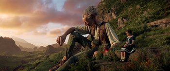 Movie still from “The BFG” (2016), directed by Steven Spielberg – An old man sitting on the ground in the middle of a field; Medium shot, Low angle