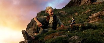 Movie still from “The BFG” (2016), directed by Steven Spielberg – An old man sitting on the ground next to a hill; Wide shot, Low angle