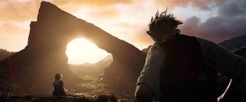 Movie still from “The BFG” (2016), directed by Steven Spielberg – A person standing in front of a mountain with a sunset in the background; Wide shot, Low angle
