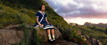 Movie still from “The BFG” (2016), directed by Steven Spielberg – A young girl sitting on a rock in a field; Wide shot, Low angle
