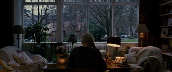 Movie still from “The Best Exotic Marigold Hotel” (2011), directed by John Madden – An older woman sitting at a desk in front of a window; Wide shot, High angle