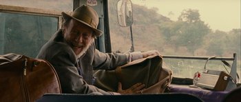 Movie still from “The Best Exotic Marigold Hotel” (2011), directed by John Madden – An older man sitting in a bus with a bag; Medium shot, Over the shoulder angle