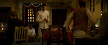 Movie still from “The Best Exotic Marigold Hotel” (2011), directed by John Madden – A man standing in front of a dining room table; Wide shot, Over the shoulder angle