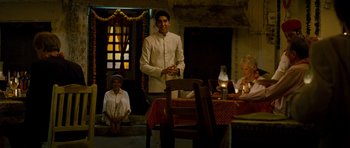 Movie still from “The Best Exotic Marigold Hotel” (2011), directed by John Madden – A man standing in front of a table with candles; Wide shot, Over the shoulder angle