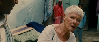 Movie still from “The Best Exotic Marigold Hotel” (2011), directed by John Madden – An older woman sitting on a bed in a room; Close Up shot, Over the shoulder angle